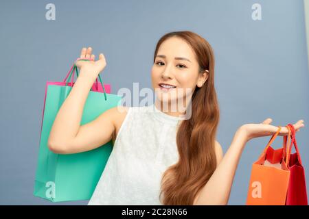 Schöne junge Frau mit Einkaufstaschen auf blau isoliert Stockfoto