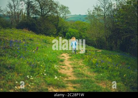 Ein kleiner Vorschulkinder läuft an einem sonnigen Frühlingstag auf einer Wiese Stockfoto