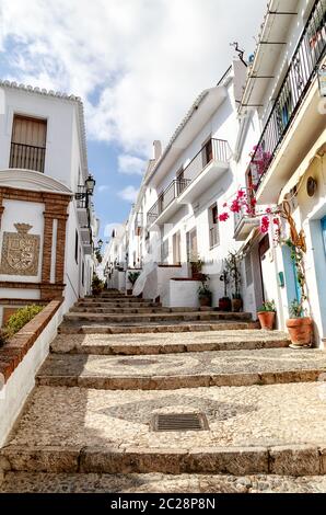 Eine schmale, steile gepflasterte Gasse in Frigiliana, einem alten maurischen Dorf oberhalb von Nerja, einem der berühmten "Weißen Dörfer" Andalusiens an der Costa del Sol, Provinz Malaga in Südspanien. Stockfoto