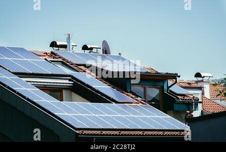 Blau-schwarze Solarzellen und Photovoltaikzellen auf dem Dach eines Mehrfamilienhauses Stockfoto
