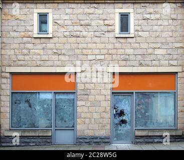 Zwei leere verlassene Geschäfte auf einer Straße mit weiß getünchten leeren Fenstern und leeren Ladenschildern Stockfoto