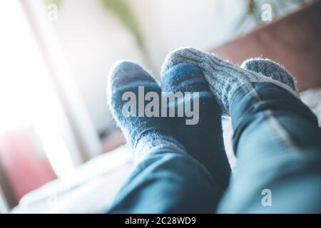 Gemütlich entspannen im Winter zu Hause: Paar mit Wollsocken liegt auf der Couch Stockfoto