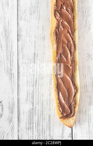 Die Hälfte der Baguette mit Schokoladencreme auf dem hölzernen Tisch Stockfoto