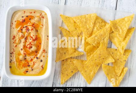 Schüssel mit Hummus mit Tortilla Chips auf dem hölzernen Tisch Stockfoto