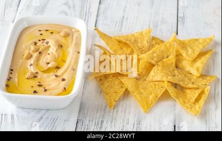 Schüssel mit Hummus mit Tortilla Chips auf dem hölzernen Tisch Stockfoto