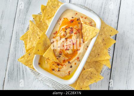 Schüssel mit Hummus mit Tortilla Chips auf dem hölzernen Tisch Stockfoto