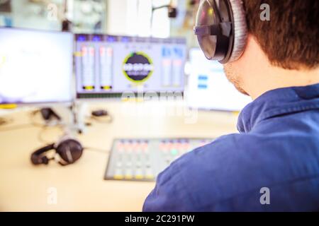 Radiomoderator sitzt in einem modernen Sendestudio und spricht ins Mikrofon Stockfoto