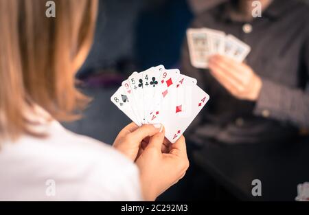 Freunde spielen zu Hause Karten zusammen. Frau hält Karten in den Händen, Mann im verschwommenen Hintergrund. Stockfoto