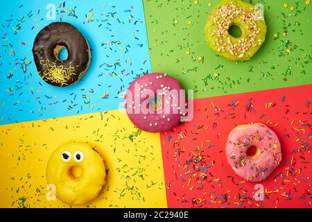 Runde Donuts mit verschiedenen Füllungen und Streuseln auf eine abstrakte Farbe Hintergrund mit festlichen Dekor Stockfoto