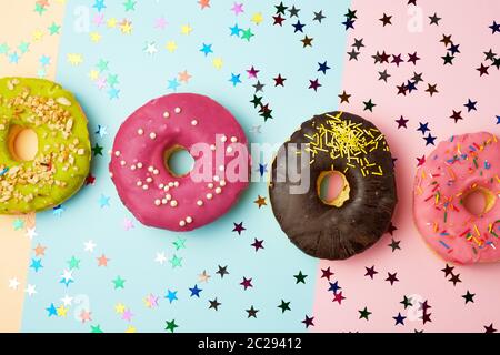 Runde Donuts mit verschiedenen Füllungen und Streuseln auf eine abstrakte Farbe Hintergrund mit festlichen Dekor, Banner Stockfoto