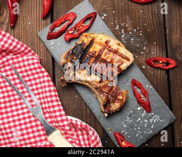 Stück gebratenes Schweinefilet auf ein Knochen liegt auf einem schwarzen Brett, saftiges Fleisch, Nahaufnahme Stockfoto