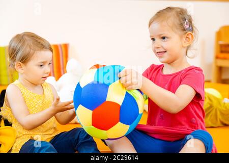 Zwei Mädchen in der Spielschule Spaß mit einem bunten Ball Stockfoto