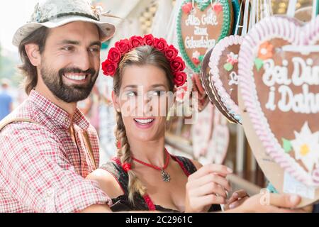 Paar in der richtigen Tracht kaufen Lebkuchenherzen der bayerischen Messe Stockfoto