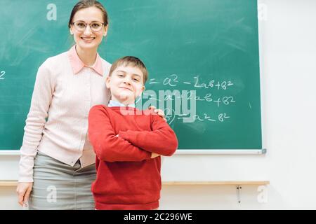 Brillanter Schuljunge ist stolz auf seine Arbeit und so ist der Lehrer beide vor dem Brett stehen Stockfoto