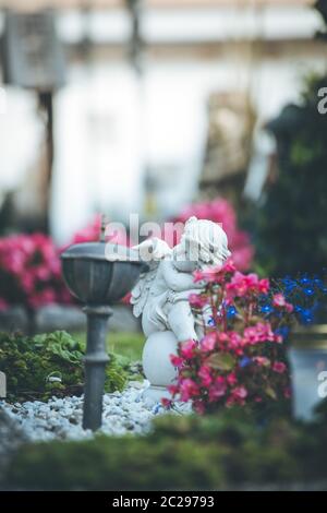 Engel auf dem Friedhof, Grab mit offenem Buch aus, Blumen Stockfoto