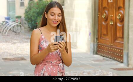 Lächelnd elegante touristische Frau Eingabe am Handy auf der Straße. Stockfoto