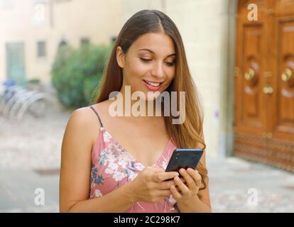 Lächelnd elegante touristische Frau Eingabe am Handy auf der Straße. Stockfoto