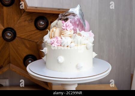 Eleganter weißer Kuchen mit Isomalt, Schokolade, Makronen, Baisalgen, Rosa und Silber Elementen. Stockfoto