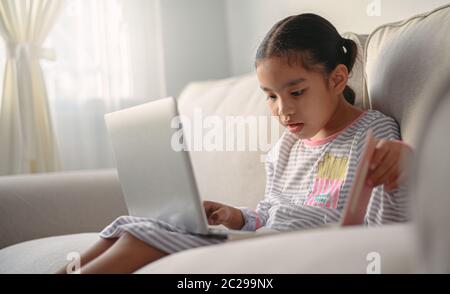 Mädchen Studentin sitzt am Tisch, schreiben Hausaufgaben . Teen mit Laptop-Computer zu studieren.New normal.Social Distanzing.zu Hause bleiben Stockfoto