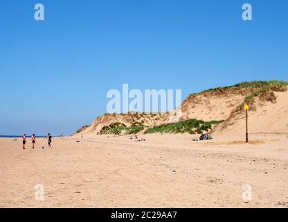 Blick auf den langen Sandstrand in formby merseyside an einem hellen Sommertag mit blauen Himmel Sanddünen und Menschen Sonnenbaden und pl Stockfoto