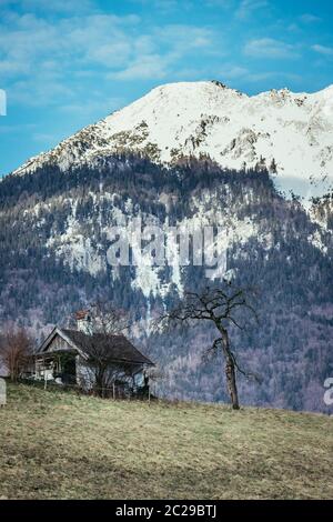 Altes Haus auf einem Hügel, schneebedeckten Berge im Hintergrund Stockfoto