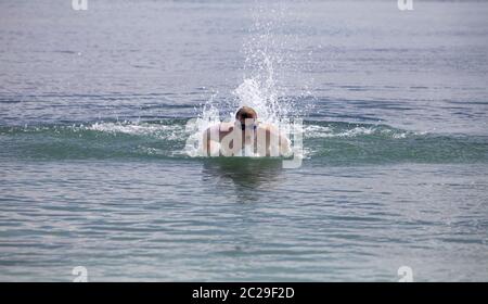 Junger Mann in Sportbrille schwimmt im Meerschmetterling-Stil Stockfoto