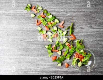 Fliegender Salat auf Holz in Schüssel, in Scheiben geschnittene Gurken-Tomatenblätter, grüne Zwiebel, Leinsamen Stockfoto