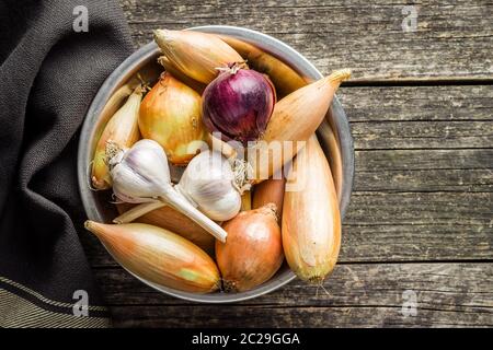 Die goldenen Schalotten und Zwiebeln und Knoblauch. Frische Birnen in der Schüssel. Ansicht von oben. Stockfoto