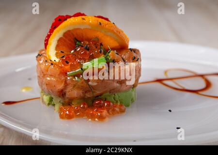 Nahaufnahme von Lachs und Avocado-Tartare mit Wakame-Algen, Erdbeeren und Lumpfish-Rogen serviert. Asiatische Küche Stockfoto