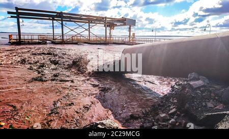 Das Industrieabwasser wird aus dem Rohr in das Wasser geleitet. Foto auf dem Handy. Stockfoto