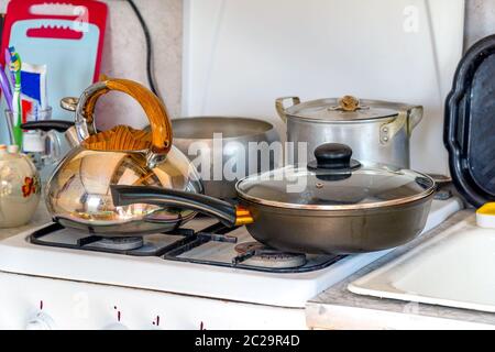 Töpfe, Pfannen und einen Wasserkocher auf dem Gasherd. Gerichte in der Küche Stockfoto