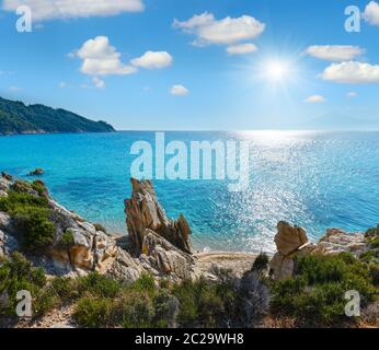 Sonniger Sandstrand und felsige Küste Stockfoto