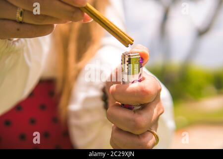 Nahaufnahme der Hand einer Frau, die Weihrauch verbrennt. Der Hintergrund ist ein unidentifiziertes Gräber, verschwommen Stockfoto