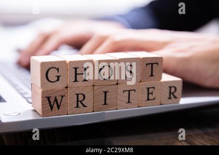 Ghostwriter Holzklotz auf dem Computer Tastatur, während jemand eingeben Stockfoto