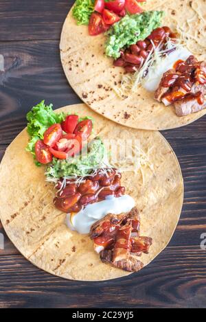 Tacos mit Füllungen auf dem hölzernen Tisch Stockfoto