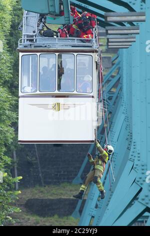 Dresden, Deutschland. Juni 2020. Ein Teilnehmer einer Abseilübung der Dresdner Feuerwehr wird von einem Wagen der historischen Schwebebahn auf zehn Metern Höhe auf halbem Weg zwischen Talstation und Bergstation abgehängt. Einmal im Jahr übt die Feuerwehr gemeinsam mit dem Verkehrsamt Dresden (DVB) die Abseilung von Fahrgästen in Not aus einem Wagen der 1901 gebauten Schwebebahn. Quelle: Sebastian Kahnert/dpa-Zentralbild/ZB/dpa/Alamy Live News Stockfoto