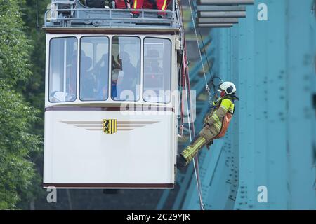 Dresden, Deutschland. Juni 2020. Ein Teilnehmer einer Abseilübung der Dresdner Feuerwehr wird von einem Wagen der historischen Schwebebahn auf zehn Metern Höhe auf halbem Weg zwischen Talstation und Bergstation abgehängt. Einmal im Jahr übt die Feuerwehr gemeinsam mit dem Verkehrsamt Dresden (DVB) die Abseilung von Fahrgästen in Not aus einem Wagen der 1901 gebauten Schwebebahn. Quelle: Sebastian Kahnert/dpa-Zentralbild/ZB/dpa/Alamy Live News Stockfoto