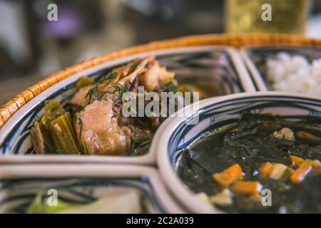 Reisschüssel mit Rattan, innen ist traditionelles vietnamesisches Mittagessen, Reis, Suppe, salziges Essen. Die Szene ist sparsam und friedlich. Essen und Trinken Konzept. Stockfoto