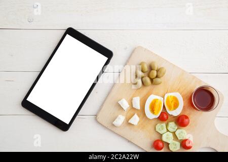 Tablette, Tee und türkisches, mediterranes Frühstück vor dem Start des Arbeitstages oder während der Arbeit auf einem hellen Holztablett auf einem Stockfoto