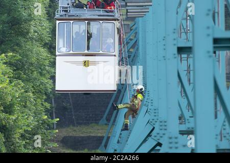 Dresden, Deutschland. Juni 2020. Ein Teilnehmer einer Abseilübung der Dresdner Feuerwehr wird von einem Wagen der historischen Schwebebahn auf zehn Metern Höhe auf halbem Weg zwischen Talstation und Bergstation abgehängt. Einmal im Jahr übt die Feuerwehr gemeinsam mit dem Verkehrsamt Dresden (DVB) die Abseilung von Fahrgästen in Not aus einem Wagen der 1901 gebauten Schwebebahn. Quelle: Sebastian Kahnert/dpa-Zentralbild/ZB/dpa/Alamy Live News Stockfoto