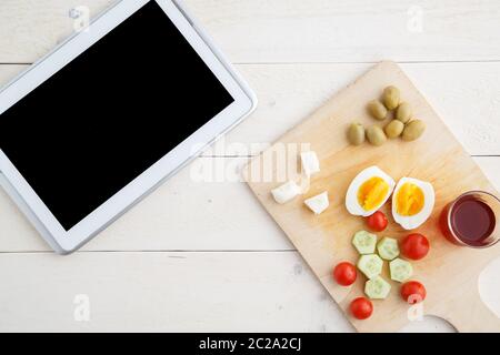 Tablette, Tee und türkisches, mediterranes Frühstück vor dem Start des Arbeitstages oder während der Arbeit auf einem hellen Holztablett auf einem Stockfoto