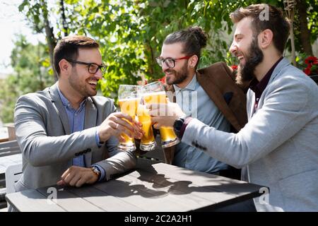 Junge Geschäftsleute trinken Bier, reden und lächeln, während sie sich in der Kneipe ausruhen Stockfoto