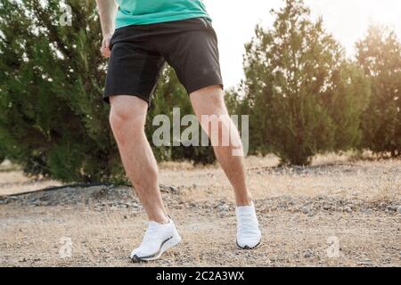 Die Füße der Männer in weißen Turnschuhen über unebenes Gelände laufen. Querfeldein laufen mit Fokus auf die Beine Runner. Stockfoto