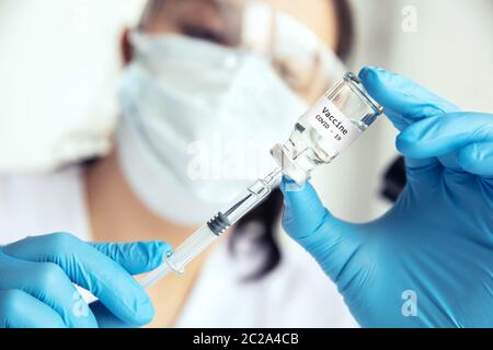 Wissenschaftler zieht Medizin in die Spritze. Die Wissenschaftlerin zieht in Schutzmaske, Brille und Handschuhen den Covid-19-Impfstoff in die Spritze. Stockfoto