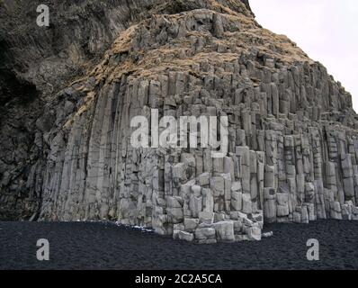 Felswand mit Basaltsteinen und schwarzem Sand in Island Stockfoto