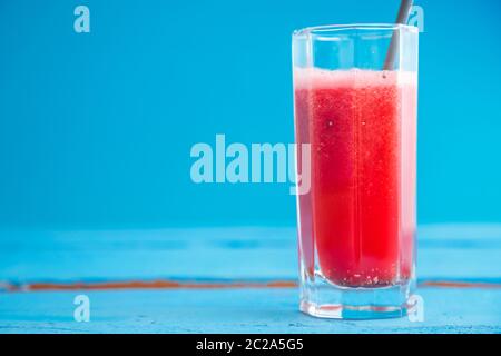 Smoothies, frisch gepressten Wassermelone Saft in ein transparentes Glas auf einem blauen Hintergrund aus Holz Stockfoto