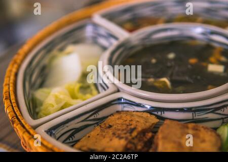 Reisschüssel mit Rattan, innen ist traditionelles vietnamesisches Mittagessen, Reis, Suppe, salziges Essen. Die Szene ist sparsam und friedlich. Essen und Trinken Konzept. Stockfoto