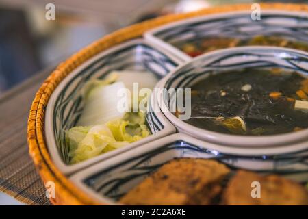 Reisschüssel mit Rattan, innen ist traditionelles vietnamesisches Mittagessen, Reis, Suppe, salziges Essen. Die Szene ist sparsam und friedlich. Essen und Trinken Konzept. Stockfoto