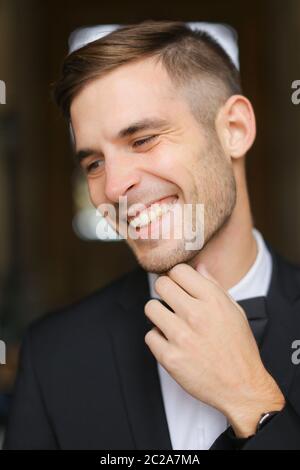 Porträt eines jungen lächelnden Mannes in schwarzem Anzug mit Fliege. Stockfoto