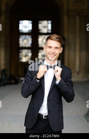 Junger europäischer Mann steht und posiert, trägt schwarzen Anzug und Krawatte. Stockfoto
